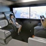 英国製の空飛ぶクルマ客室を再現した展示で、映像によるフライト体験を楽しむ親子連れ＝大阪市此花区の夢洲