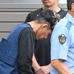 捜査員に連れられて警察車両に乗り込む谷本将志容疑者＝２４日午前９時２３分、神戸市中央区吾妻通５
