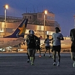 まだ夜の明けきらない中、駐機する飛行機の前を走り抜けるランナーたち＝３０日朝、神戸市中央区、神戸空港