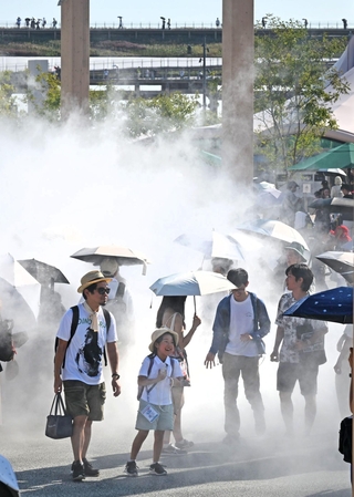 厳しい日差しが照りつける万博会場で、ミストを浴びて涼む来場者たち＝３１日午後、大阪市此花区の夢洲（撮影・大田将之）