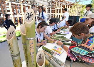 竹灯籠にメッセージを書き込む人たち＝１日午後、大阪市此花区の夢洲（撮影・斎藤雅志）