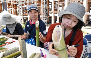 竹灯籠にメッセージを書き込む人たち＝１日午後、大阪市此花区の夢洲（撮影・斎藤雅志）