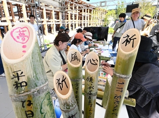 竹灯籠にメッセージを書き込む人たち＝１日午後、大阪市此花区の夢洲（撮影・斎藤雅志）