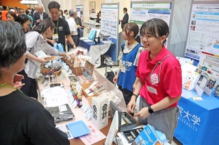 パネル展示のブースで能登の名産品などを販売する神戸学院大学の学生ら＝神戸市中央区港島１