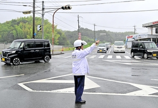 停電で信号が止まり、車両を手信号で誘導する警察官＝５日午前８時12分、淡路市竹谷