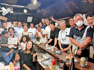 夫・正さんの写真を手にする木下和子さん（中央）を囲む常連客と家族＝神戸市兵庫区上庄通２