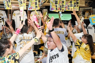 リーグ優勝が決まった瞬間。両手を挙げて喜び合うファン＝７日午後９時１１分、神戸市兵庫区大開通４、「タイガースバー　イレブン」