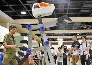 歯車で動く大型ロボットが登場し、興味津々な様子で見学する親子連れら＝バンドー神戸青少年科学館