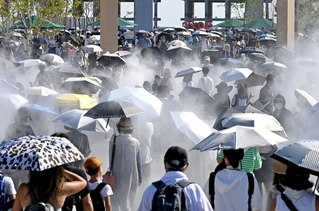 熱中症予防のため、日傘を差す家族連れら＝８月３１日、大阪市此花区の夢洲（撮影・大田将之）
