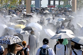 熱中症予防のため、日傘を差す家族連れら＝８月３１日、大阪市此花区の夢洲（撮影・大田将之）