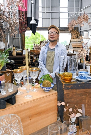 改修した空き工場に並ぶアンティーク商品と小畦雅史さん＝神戸市長田区長田天神町５