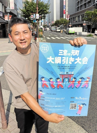 綱引き大会を実施する三宮中央通りでポスターを掲げる実行委代表の矢野克幸さん＝神戸市中央区三宮町２