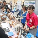 パネル展示のブースで能登の名産品などを販売する神戸学院大学の学生ら＝神戸市中央区港島１