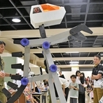 歯車で動く大型ロボットが登場し、興味津々な様子で見学する親子連れら＝バンドー神戸青少年科学館