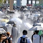 熱中症予防のため、日傘を差す家族連れら＝８月３１日、大阪市此花区の夢洲（撮影・大田将之）