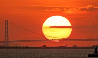 主塔の間に落ちる太陽＝６日午後、大阪市此花区の大阪・関西万博会場から（撮影・吉田敦史）