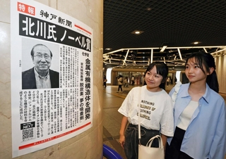 北川進氏のノーベル化学賞受賞を伝える号外を見る人たち＝８日夜、神戸市中央区、デュオこうべ（撮影・笠原次郎）