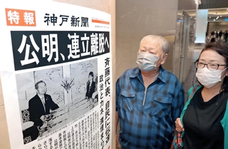 公明党の連立政権からの離脱方針を伝える号外を見る人たち＝１０日午後、神戸市中央区、デュオこうべ（撮影・中西幸大）