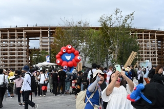 東ゲート付近のミャクミャク像と記念撮影し、万博最終日のスタートを切る来場者ら＝１３日午前、大阪市此花区の夢洲（撮影・大田将之）