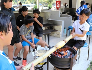 約１００年前の製法でバウムクーヘンを作る子どもたち＝広島市南区、ユーハイム似島歓迎交流センター