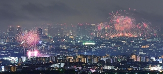 １０月１８日に同時に開催された伊丹（左）と淀川の花火大会。大輪が市街地を彩った＝宝塚市内から望む