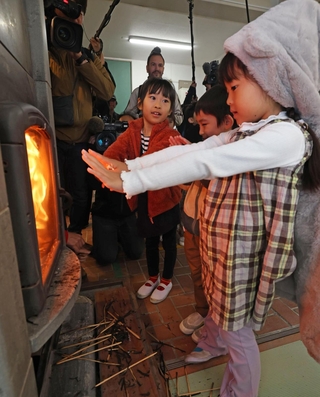火がともったストーブで暖を取る児童たち＝２３日午前、神戸市灘区六甲山町、六甲山小学校（撮影・鈴木雅之）