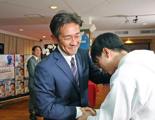 落選確実の一報を受け、支援者と握手を交わす五島大亮氏＝２６日夜、神戸市中央区八幡通２（撮影・鈴木雅之）