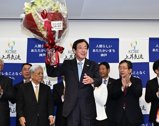 当選が確実となり、花束を持って喜ぶ久元喜造氏（中央）＝２６日夜、神戸市中央区の神戸国際会館（撮影・風斗雅博）