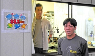 災害ＦＭ「まちのラジオ」のスタジオ前で。右は山下祐介さん