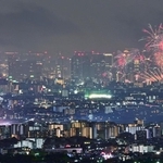 １０月１８日に同時に開催された伊丹（左）と淀川の花火大会。大輪が市街地を彩った＝宝塚市内から望む