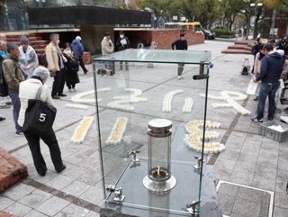 「１．１７希望の灯り」（手前）から、ろうそくで形取られた「３・１１　よりそう」に分灯された＝２０２５年３月１１日、神戸市中央区加納町６