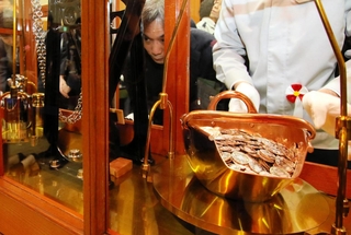 てんびんで硬貨の重さを慎重に計る職員＝大阪市北区天満１