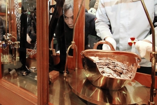 てんびんで硬貨の重さを慎重に計測する職員＝大阪市北区天満１