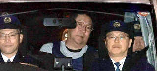 警察車両で送検される立花孝志容疑者（中央）＝１０日、神戸市中央区下山手通５