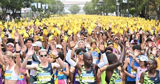 神戸マラソンのスタート地点で黄色い手袋を着け、両手を上げるランナーたち＝２０２４年１１月１７日、神戸市中央区