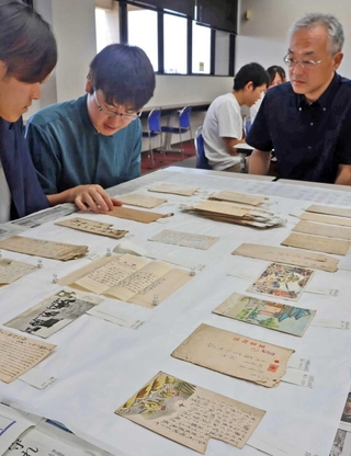 軍事郵便の研究に取り組む高久智広教授（右）と学生ら＝明石市立文化博物館