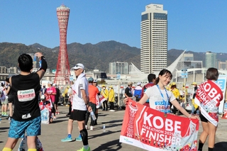 マラソンを完走し、神戸ポートタワーを背景に記念撮影するランナーたち＝神戸市中央区東川崎町１