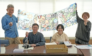 銭湯巡りのキャラクター「ゆとりっぷ」が描かれたのれんを掲げスタンプラリーをＰＲする実行委員会のメンバー＝神戸市中央区下山手通７、兵浴会館