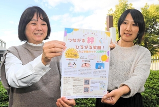 ひょうご多胎ネット20周年記念イベントのチラシを手にＰＲする天羽千恵子さん（左）ら＝神戸市西区