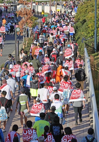 フィニッシュ地点となった神戸ハーバーランドでタオルをかけて移動するランナーたち＝１６日、神戸市中央区弁天町（撮影・笠原次郎）