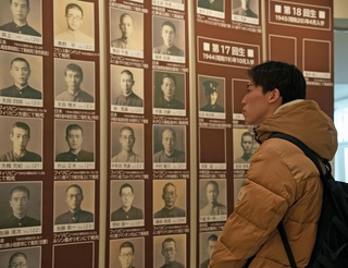 戦没学生の顔写真を見つめる神戸大の学生＝神戸大学百年記念館