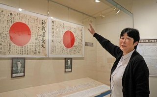 日章旗の説明をする展示の担当者＝神戸大学百年記念館