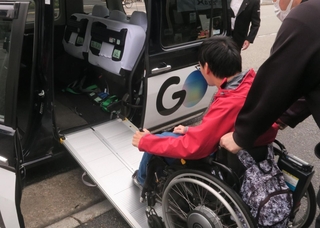 座席を折りたたみ、スロープを渡したユニバーサルデザインタクシーに乗り込む男性＝西宮市内