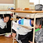 地震発生の校内放送を聞き、机の下に身を隠す児童たち＝５日午前、姫路市大塩町汐咲２