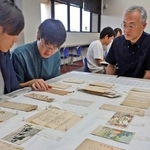 軍事郵便の研究に取り組む高久智広教授（右）と学生ら＝明石市立文化博物館