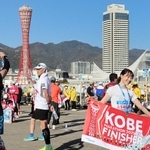 マラソンを完走し、神戸ポートタワーを背景に記念撮影するランナーたち＝神戸市中央区東川崎町１