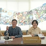 銭湯巡りのキャラクター「ゆとりっぷ」が描かれたのれんを掲げスタンプラリーをＰＲする実行委員会のメンバー＝神戸市中央区下山手通７、兵浴会館