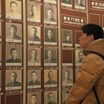 戦没学生の顔写真を見つめる神戸大の学生＝神戸大学百年記念館