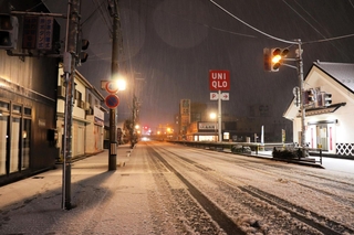 豊岡市街では３日午後８時ごろから断続的に大粒の雪が降り、数時間で１～数センチ積もった。道行く人の姿はほとんどなく、乗用車はスリップしないよう徐行した＝３日午後11時８分、同市若松町