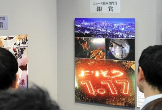 ニュース組み部門銀賞を受賞した神戸新聞社の「光　よりそう30年」などの写真に見入る来場者＝５日午前、大阪市中央区